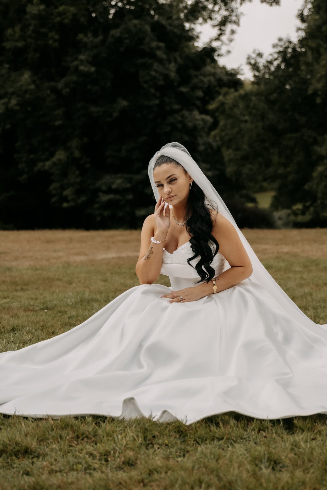 La mariée assise dans l'herbe, main sur le cœur